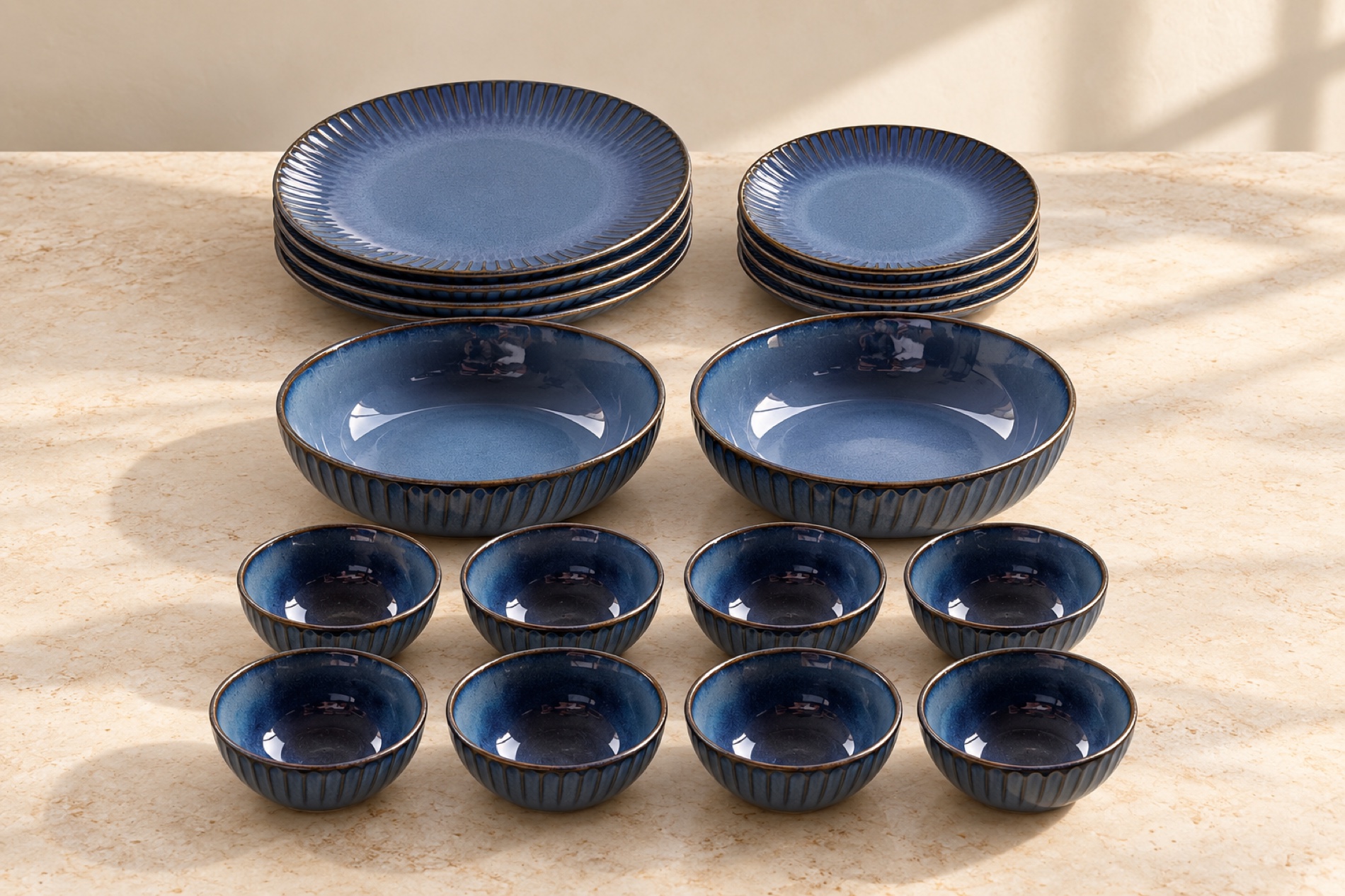 The 18-piece dinner set in Blue, arranged with four large plates, four quarter plates, two serving bowls and eight small bowls