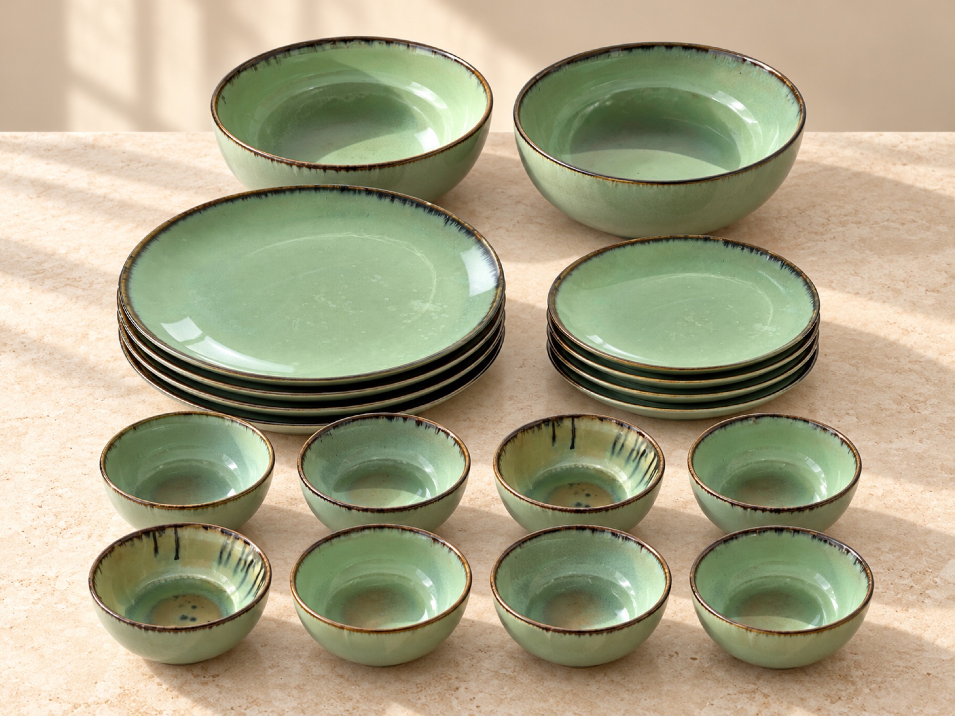 The 18-piece dinner set in Sage, arranged with four large plates, four quarter plates, two serving bowls and eight small bowls